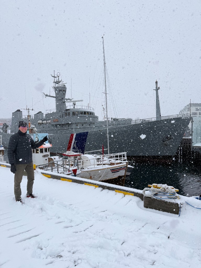 Gunnar Birgisson standing at a snowy harbor in front of an Icelandic Coast Guard vessel